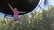 Charger l&#39;image dans la visionneuse de galerie, young girl jumping high on a trampoline with sun shade
